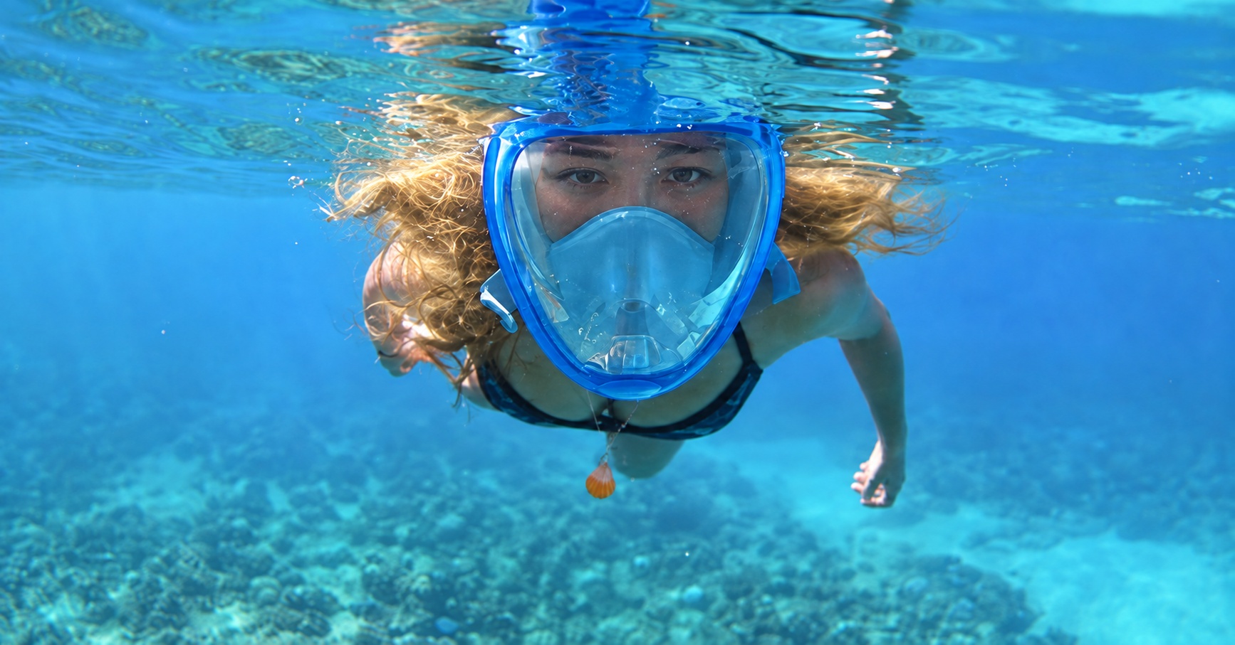 Blonde swimmer exploring turquoise water in a blue full-face snorkel mask
